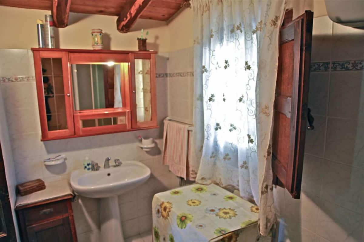 A bathroom with a wooden cabinet, a sink, and a floral tablecloth.