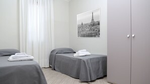 Habitación de hotel con dos camas, un armario y una fotografía de un paisaje urbano en la pared.