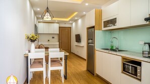 Una cocina moderna con armarios blancos, horno empotrado y refrigerador de acero inoxidable.