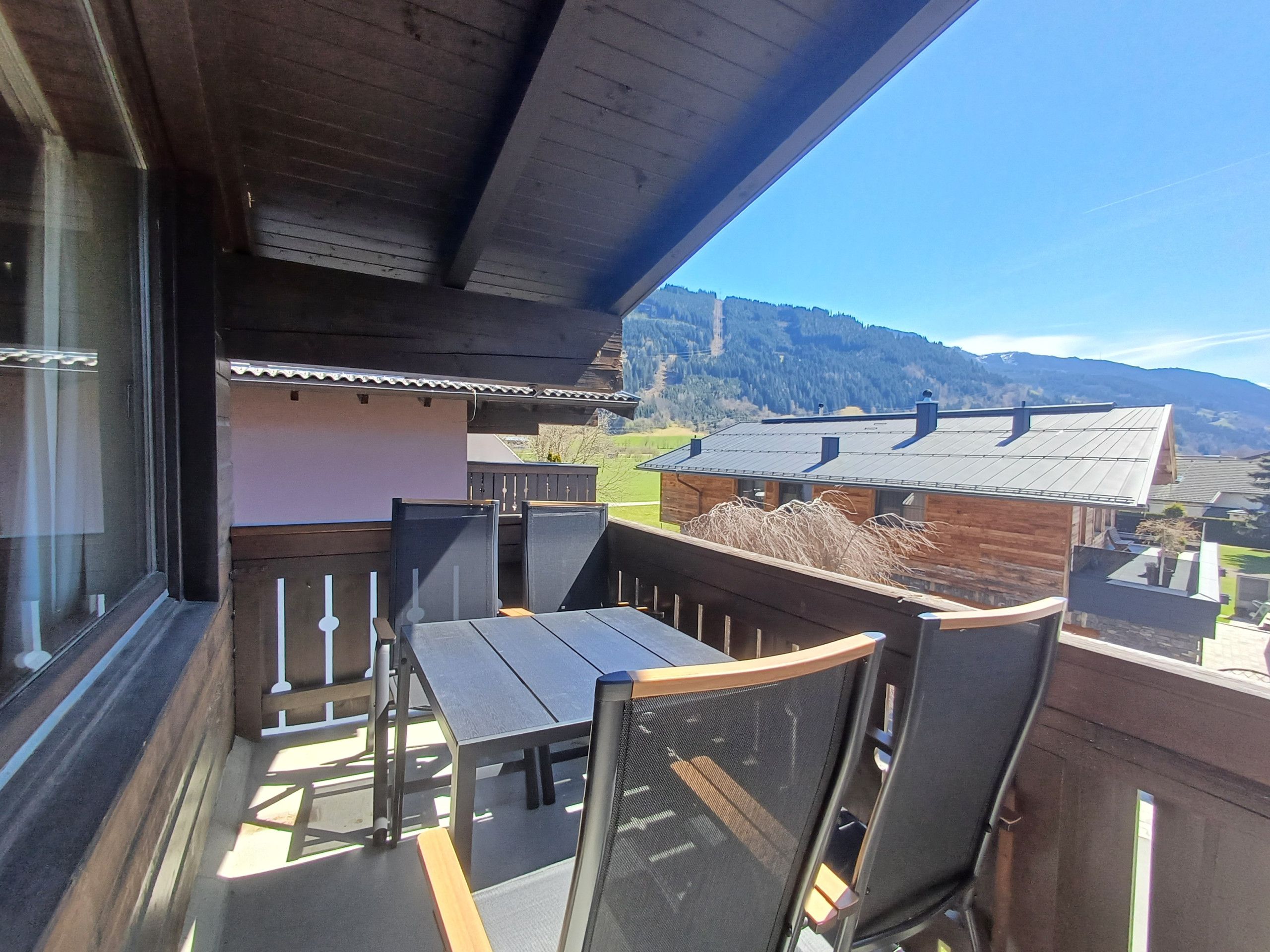 Un balcon avec une table et des chaises, donnant sur un paysage montagneux.