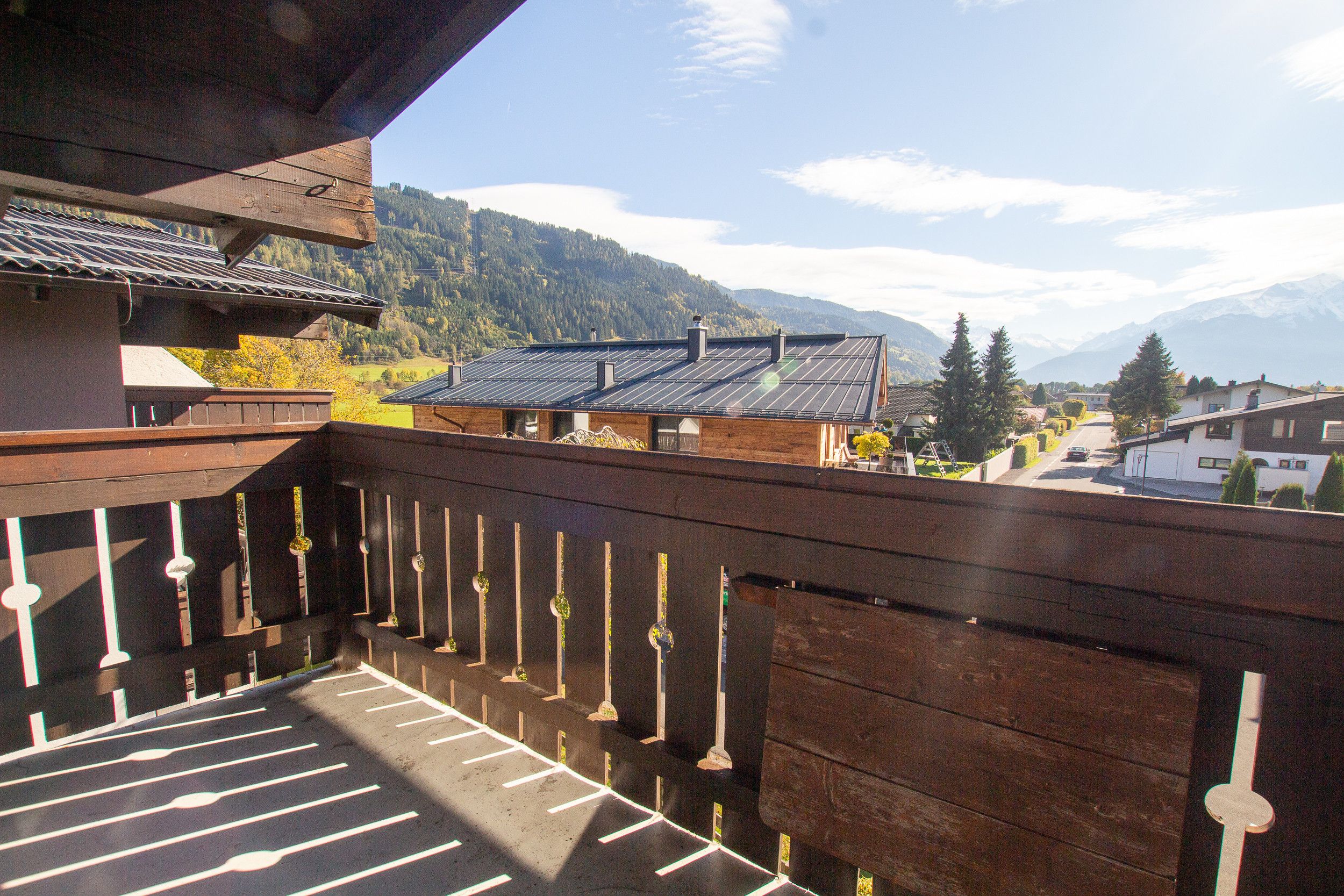 Een houten balkon met uitzicht op een berg en een dorp.