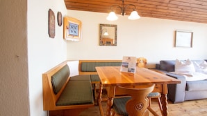 A wooden dining table with benches, a sofa, and a chandelier. - Apartment Schmid (Maishofen)