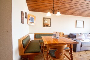 Ein Holzesstisch mit Bänken, eine Couch und eine Chandelier.