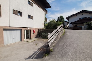 En tvåvåningsbyggnad med en garageport, en liten uteplats med ett trästaket och en asfalterad uppfart.