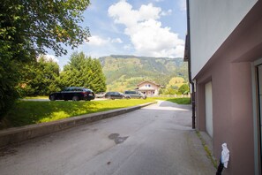 Eine Auffahrt führt zu einem Gebäude mit Blick auf einen Berg und parkenden Autos.