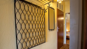 A hallway with a metal security gate, a wooden door, and a bed in the adjacent room. - Apartment Schmid (Maishofen)