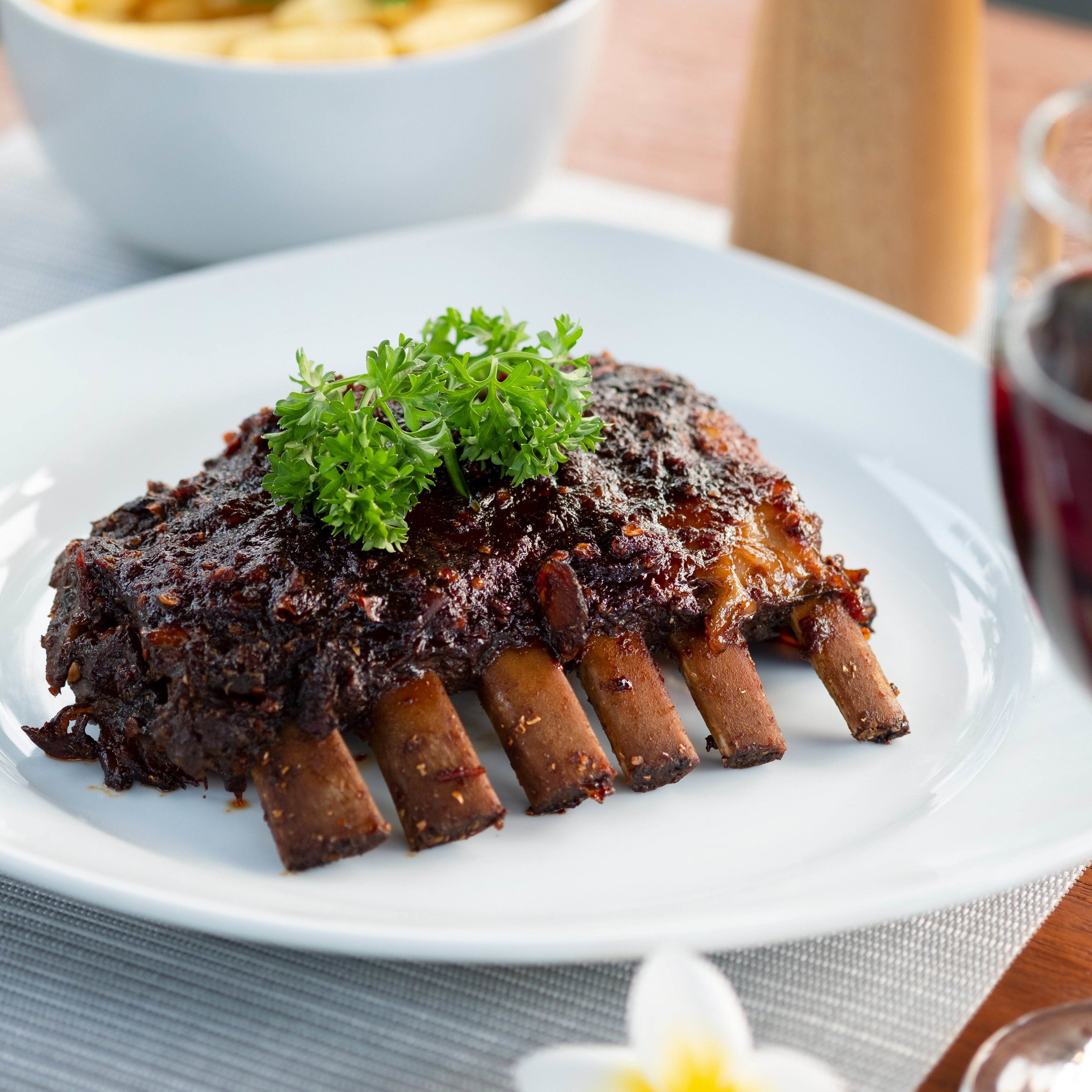 A plate of ribs garnished with parsley, served on a white plate.
