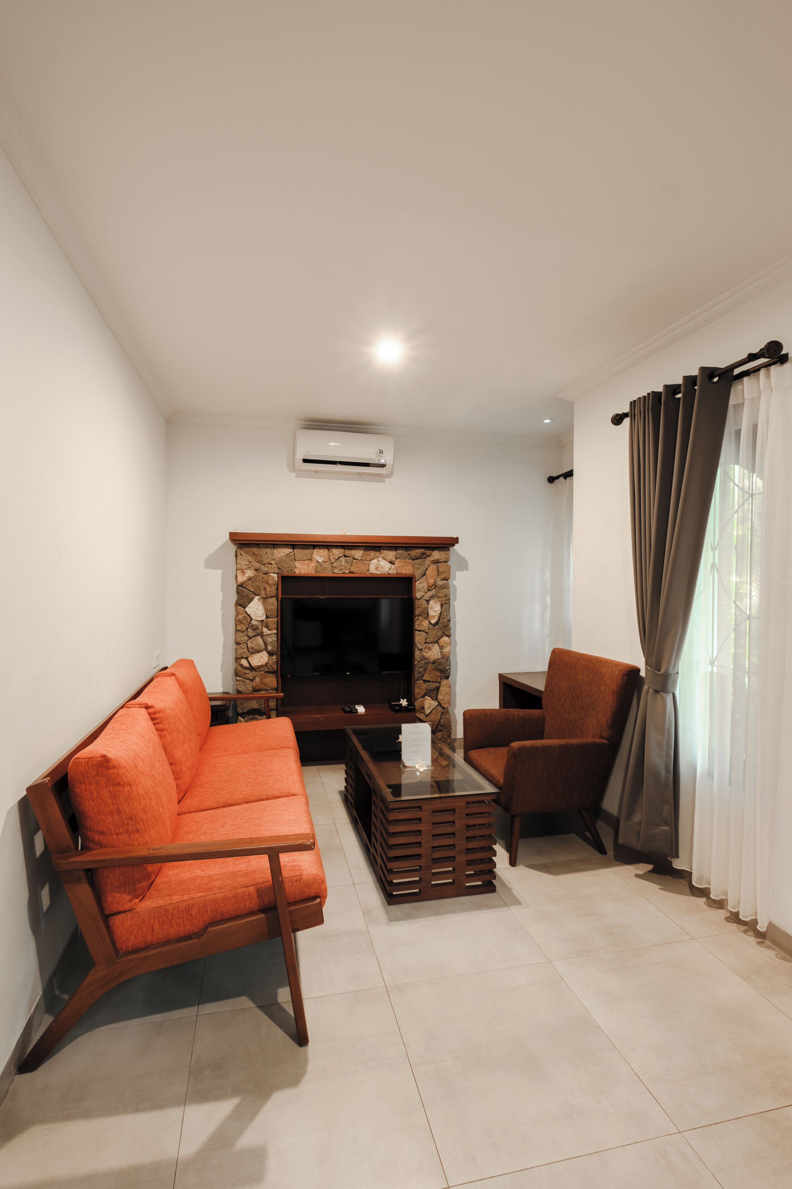 A living room with a sofa, armchair, and a stone fireplace.