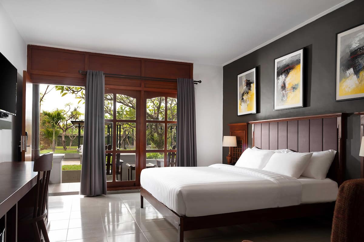 Une chambre d’hôtel avec un lit, un bureau et une vue sur l’extérieur grâce à de grandes fenêtres.