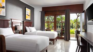 Habitación de hotel con dos camas, un escritorio, un televisor y vistas al exterior.