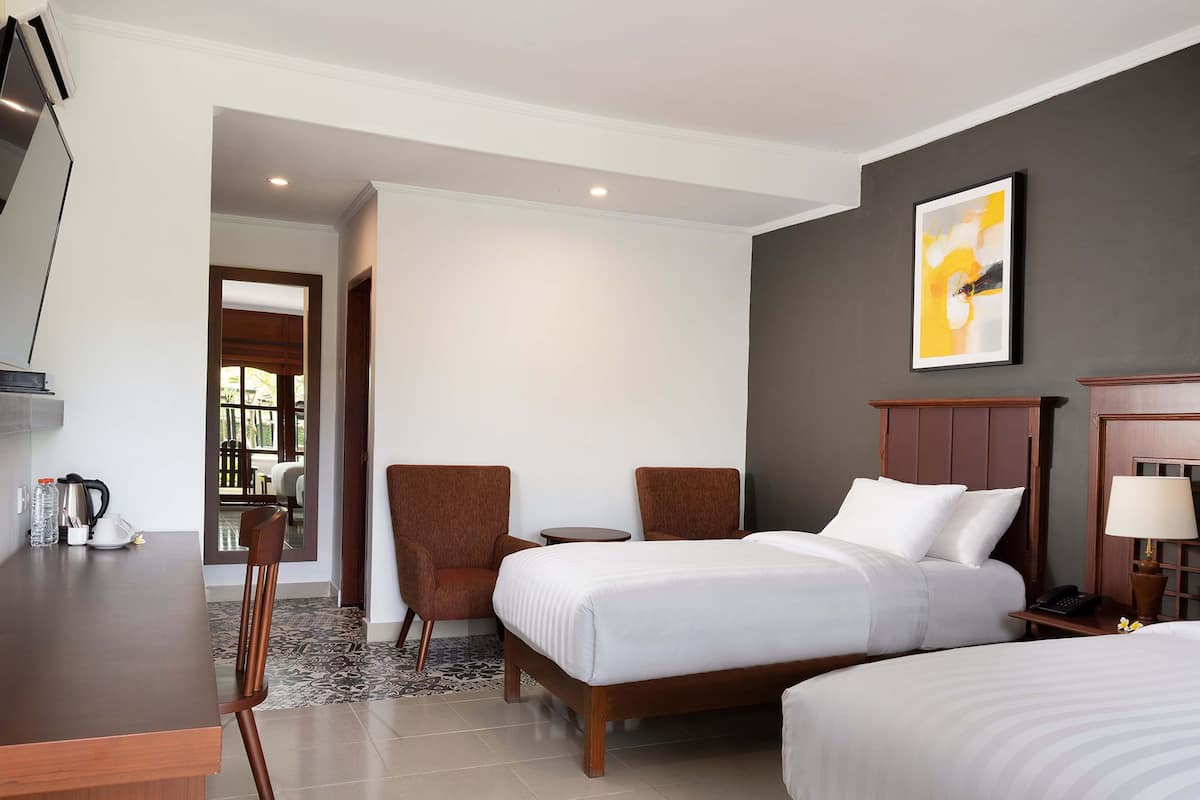 Une chambre d’hôtel avec un lit, deux chaises, un bureau, une machine à café et un tableau au mur.