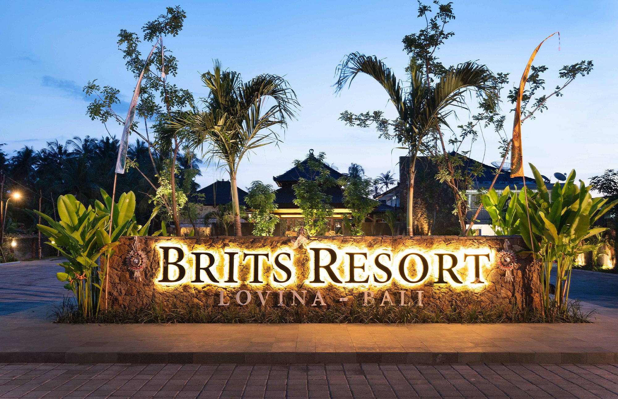 Cartell de Brits Resort a Lovina, Bali, envoltat de vegetació tropical i palmeres.
