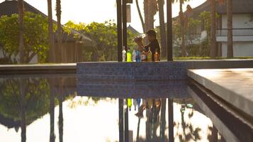 A pool with a tiled edge and a person holding a bottle.
