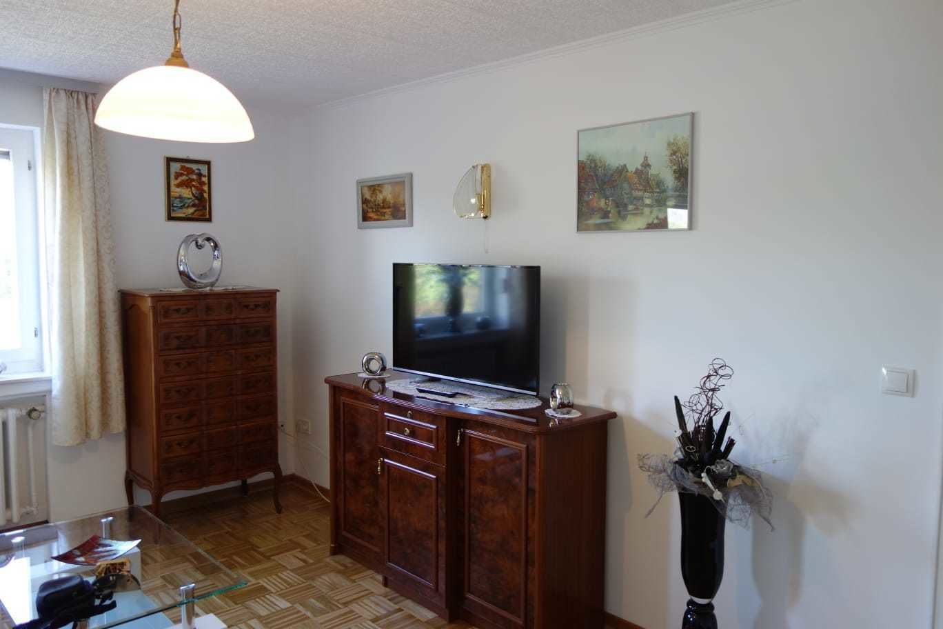 Un salon comprenant un meuble en bois, un téléviseur et un vase décoratif contenant des branches.