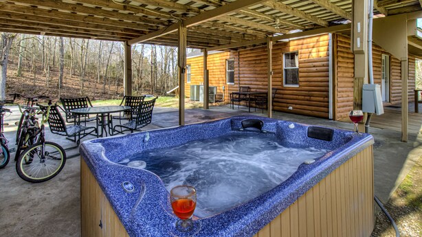 Un bain à remous, un verre de vin rouge à portée de main, entouré de meubles de jardin et de vélos.