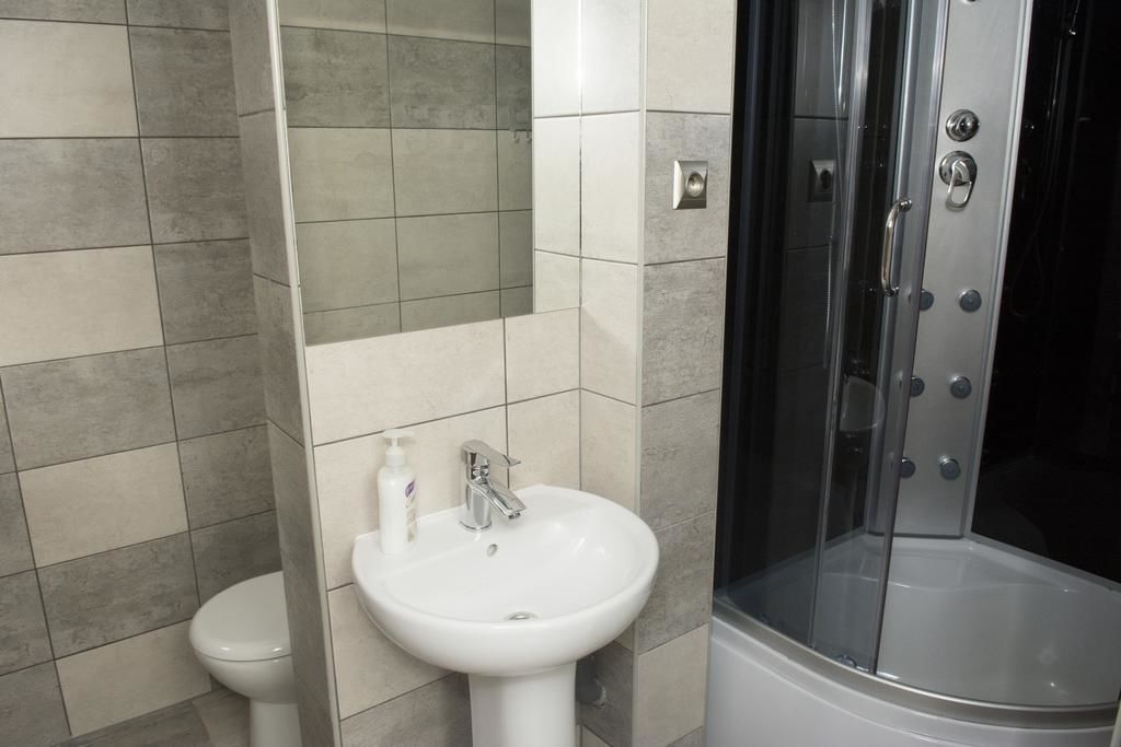 A bathroom with a white sink, a toilet, and a glass-enclosed shower.