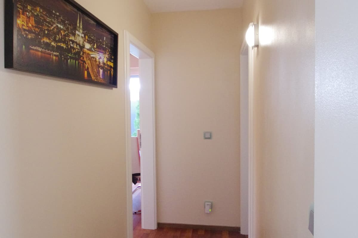 A narrow hallway with wooden flooring and beige walls.