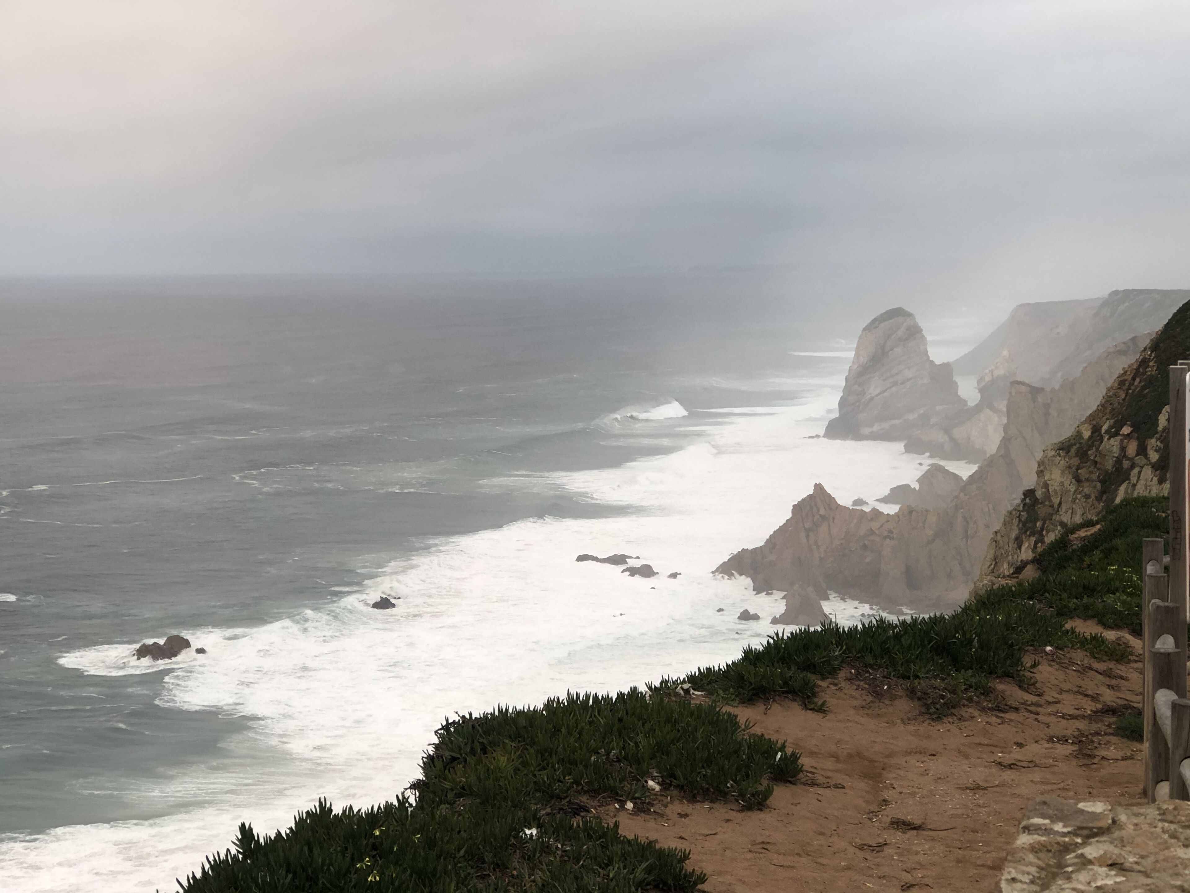 A coastal landscape with rocky cliffs and a sandy path.