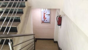 A staircase with metal railings and a fire extinguisher mounted on the wall. - Sana Heritage Inn Hyd (Hyderabad)