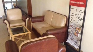 A seating area with two leather chairs and a sofa, a small glass table, and a newspaper rack with 'The Times of India' visible. - Sana Heritage Inn Hyd (Hyderabad)