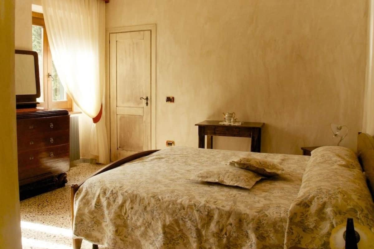 Une chambre à coucher avec un lit, une commode et une petite table avec une lampe.
