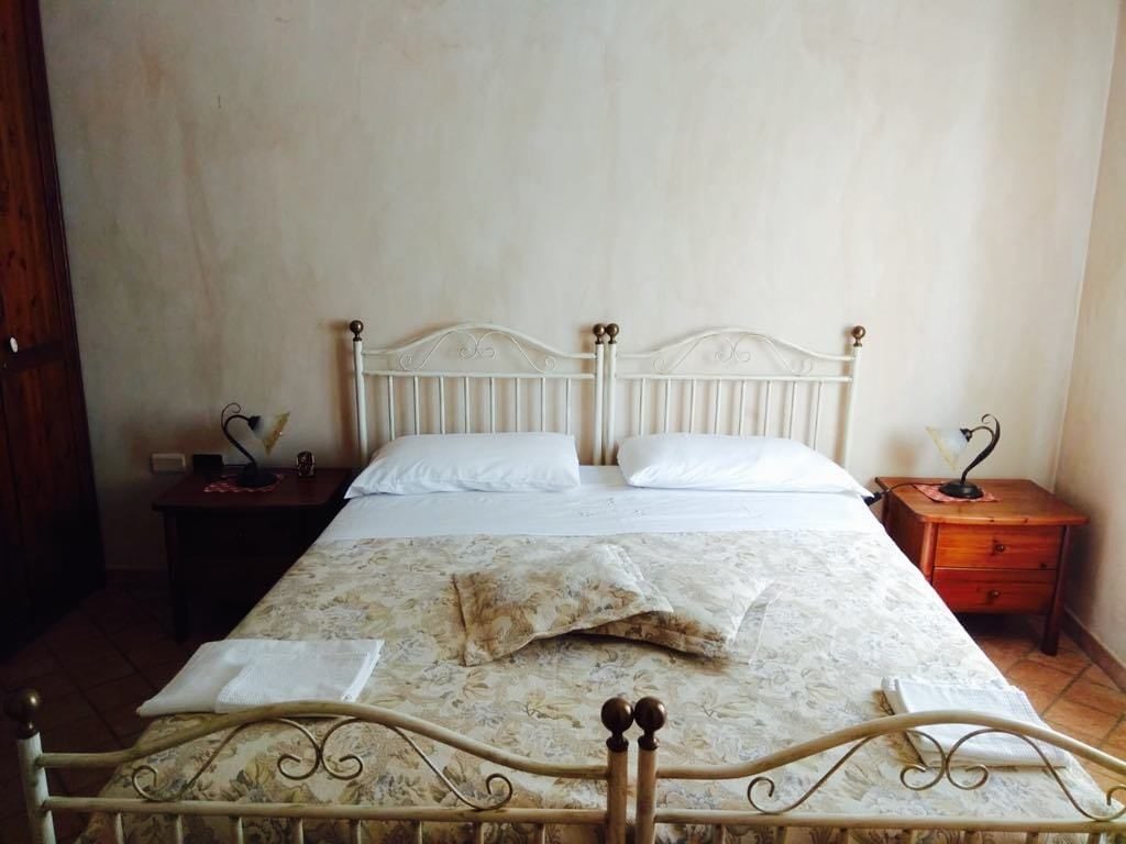 Un lit simple avec une couvre-lit à motifs floraux, deux tables de chevet et une table de chevet en bois avec une lampe.