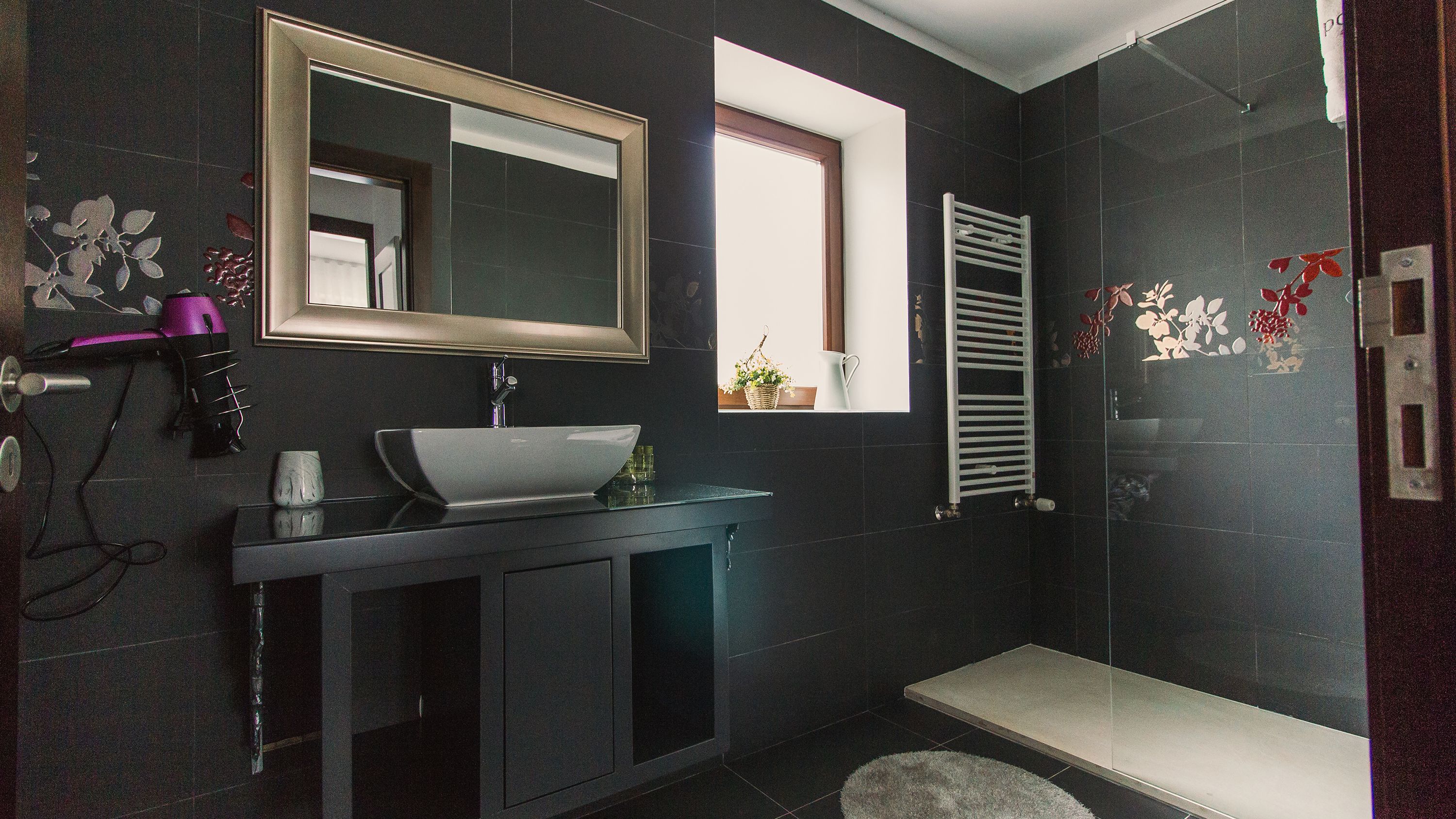 A modern bathroom with a large mirror, a sink, and a shower area.