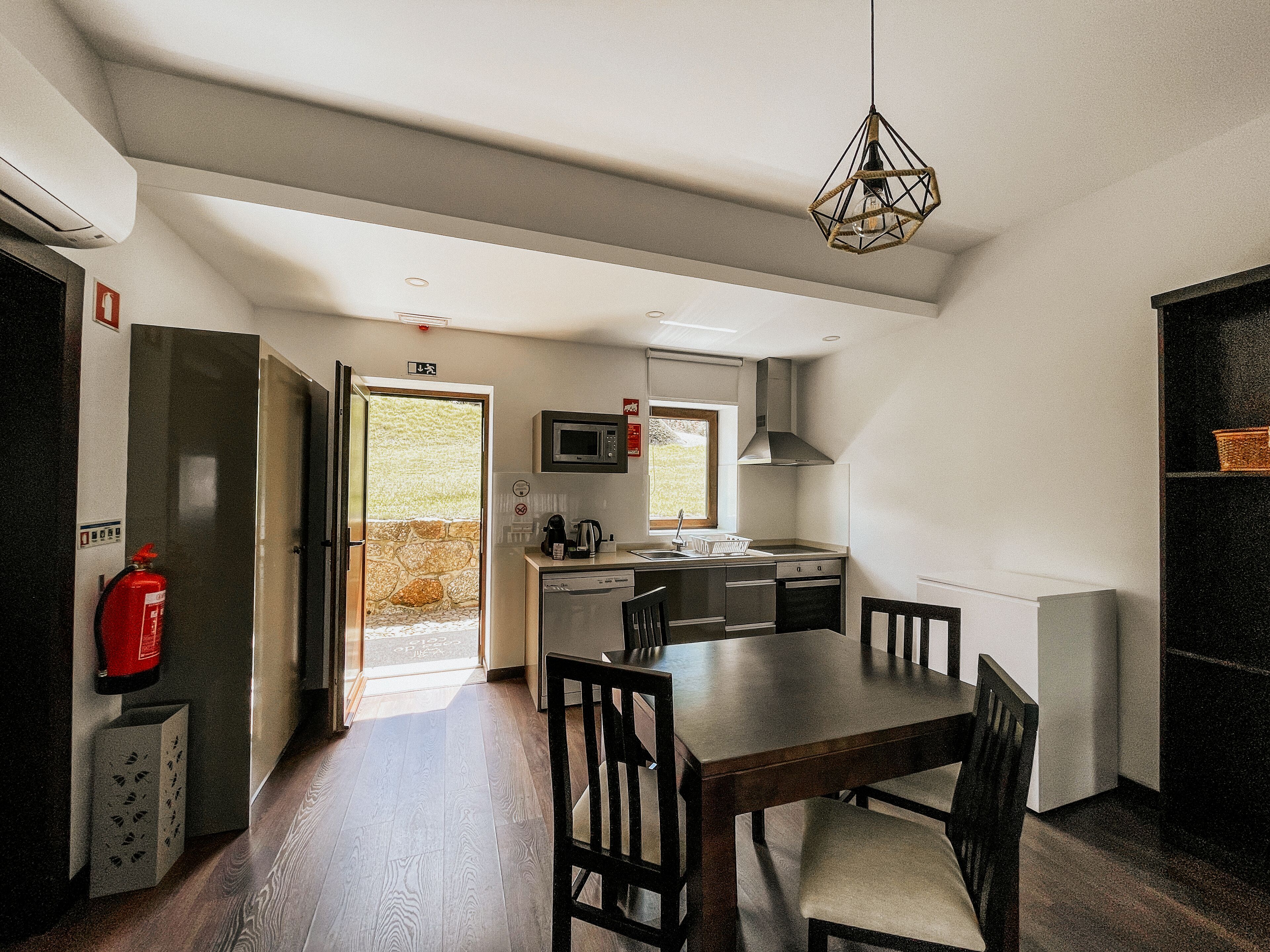 Una cocina moderna con comedor, pared de piedra y extintor.