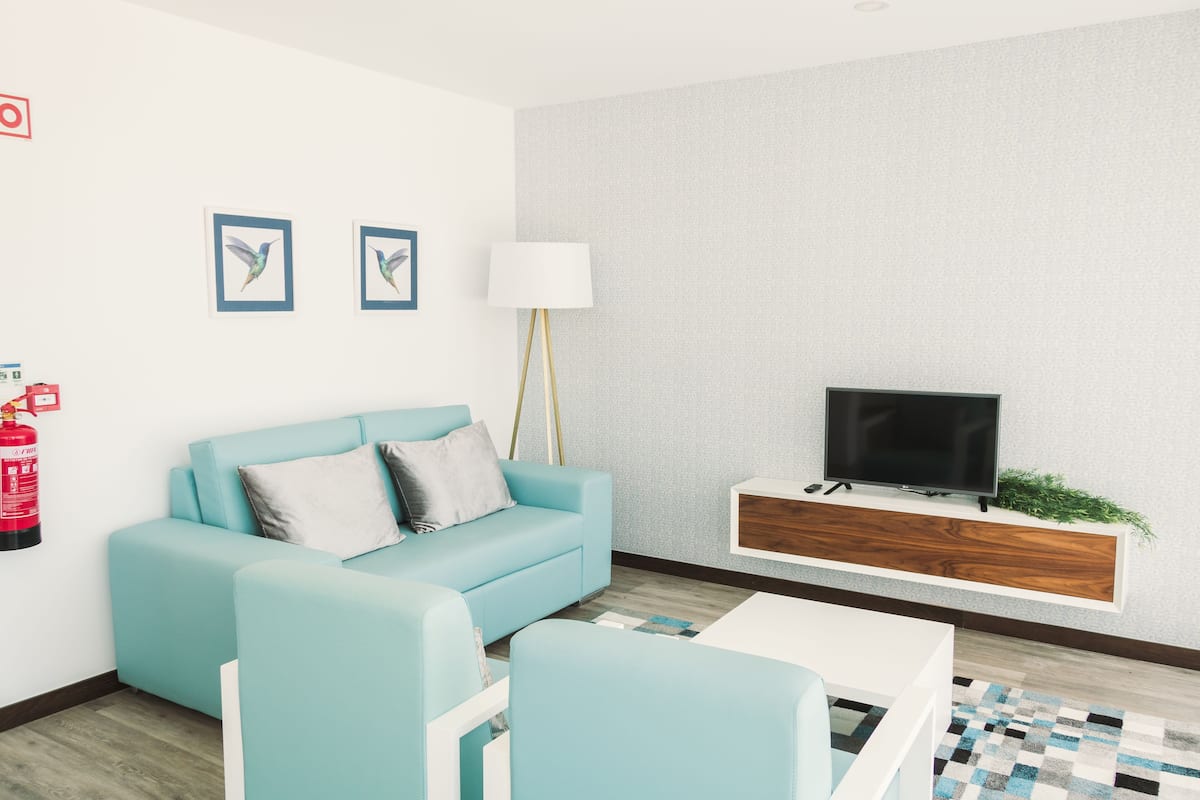 A modern living room with a light blue sofa, a white coffee table, and a mounted TV.