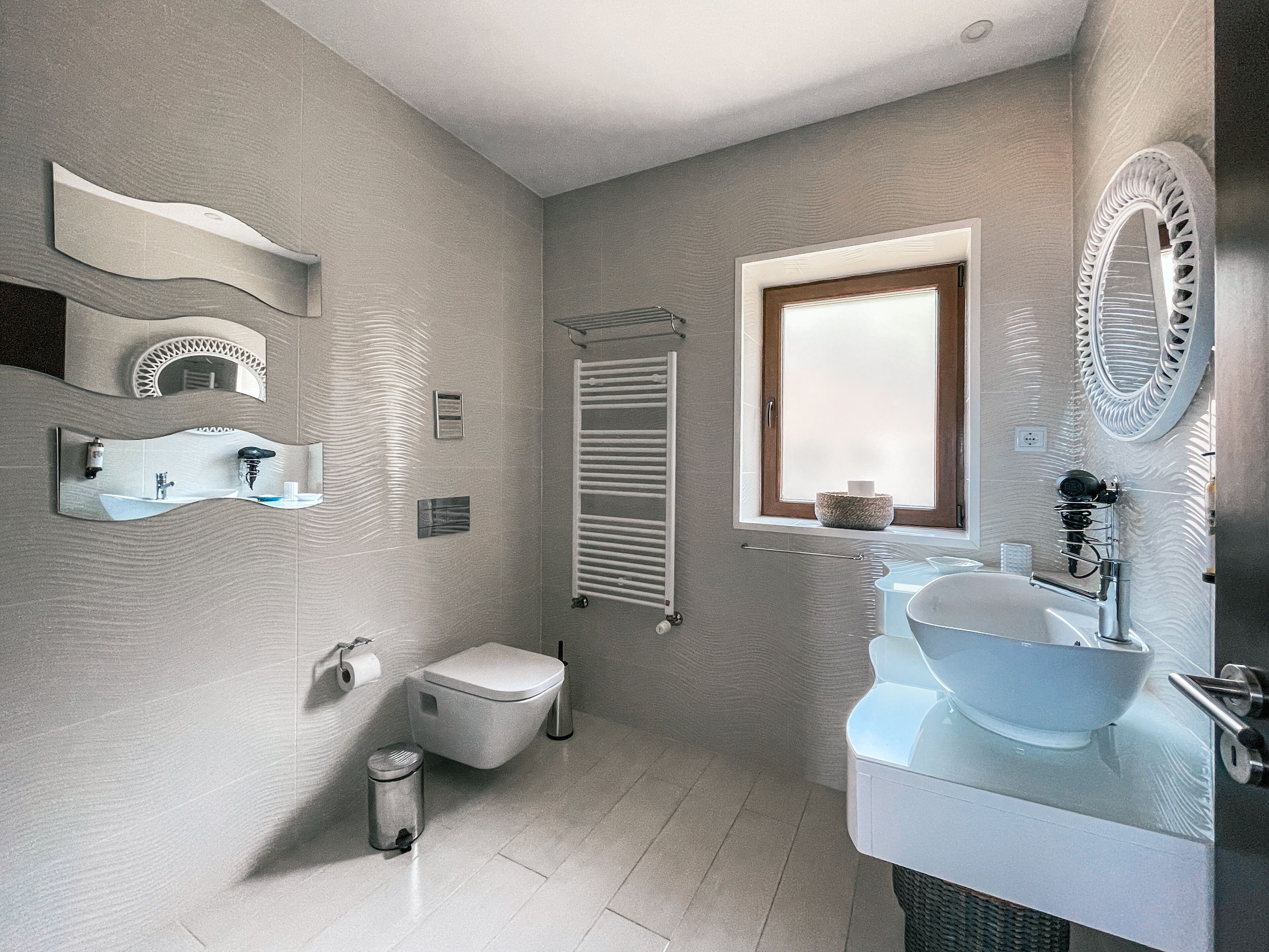 A modern bathroom with a toilet, sink, and window.