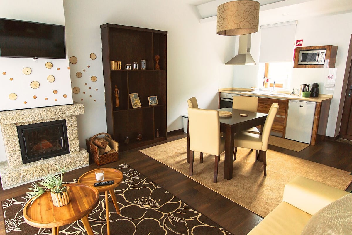 A living room with a fireplace, a dining area, and a kitchen.