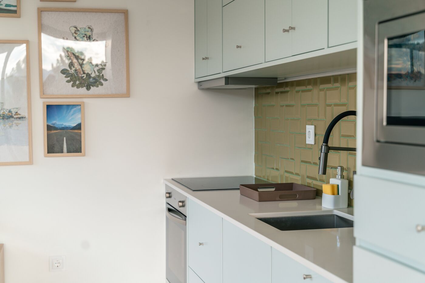A modern kitchen with light-colored cabinets, a built-in dishwasher, and a stainless steel range hood.