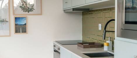 A modern kitchen with light-colored cabinets, a built-in dishwasher, and a stainless steel range hood.