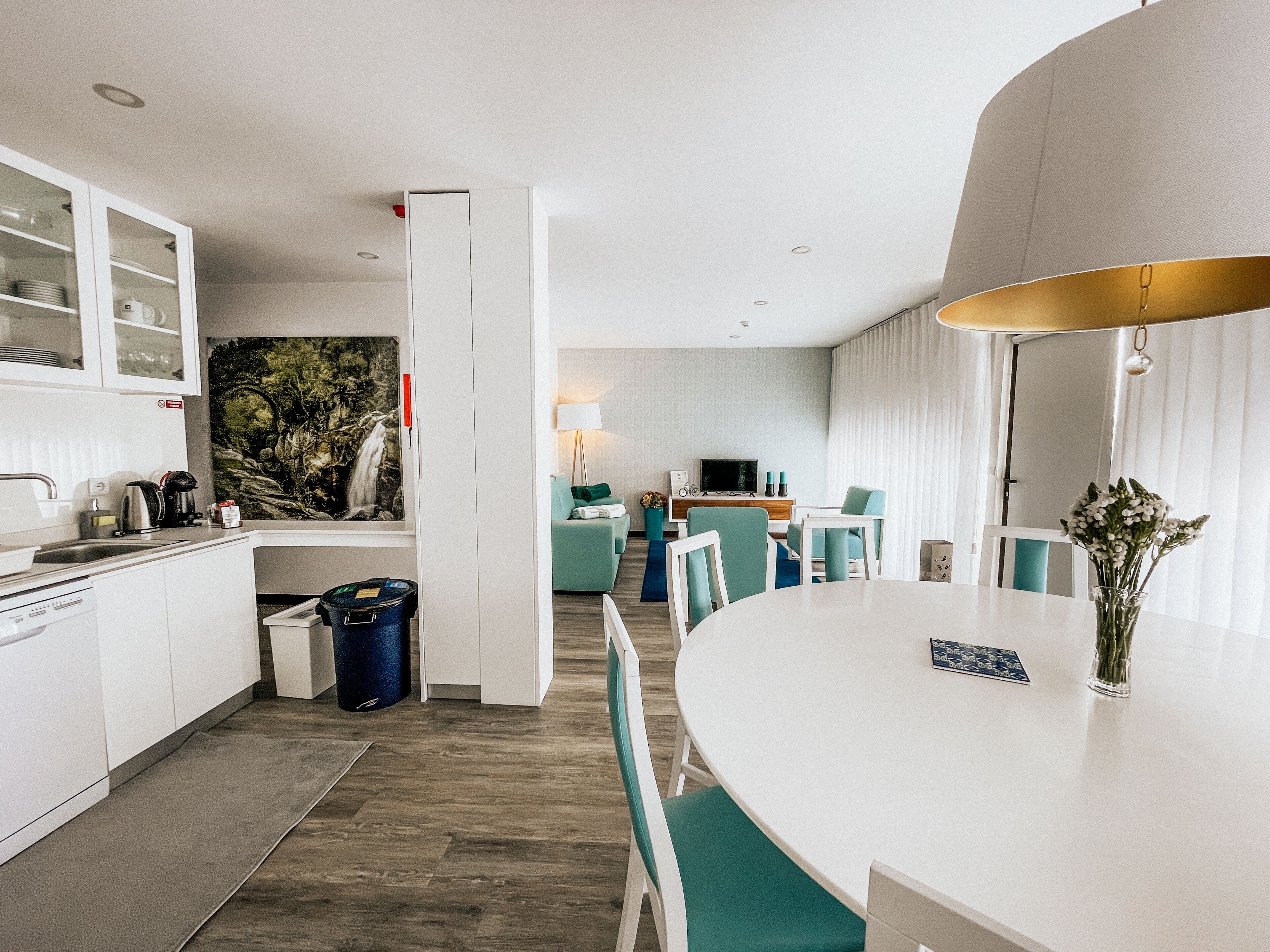 Une chambre d’hôtel moderne dotée d’une cuisine, d’un coin repas et d’une grande fenêtre avec des rideaux.