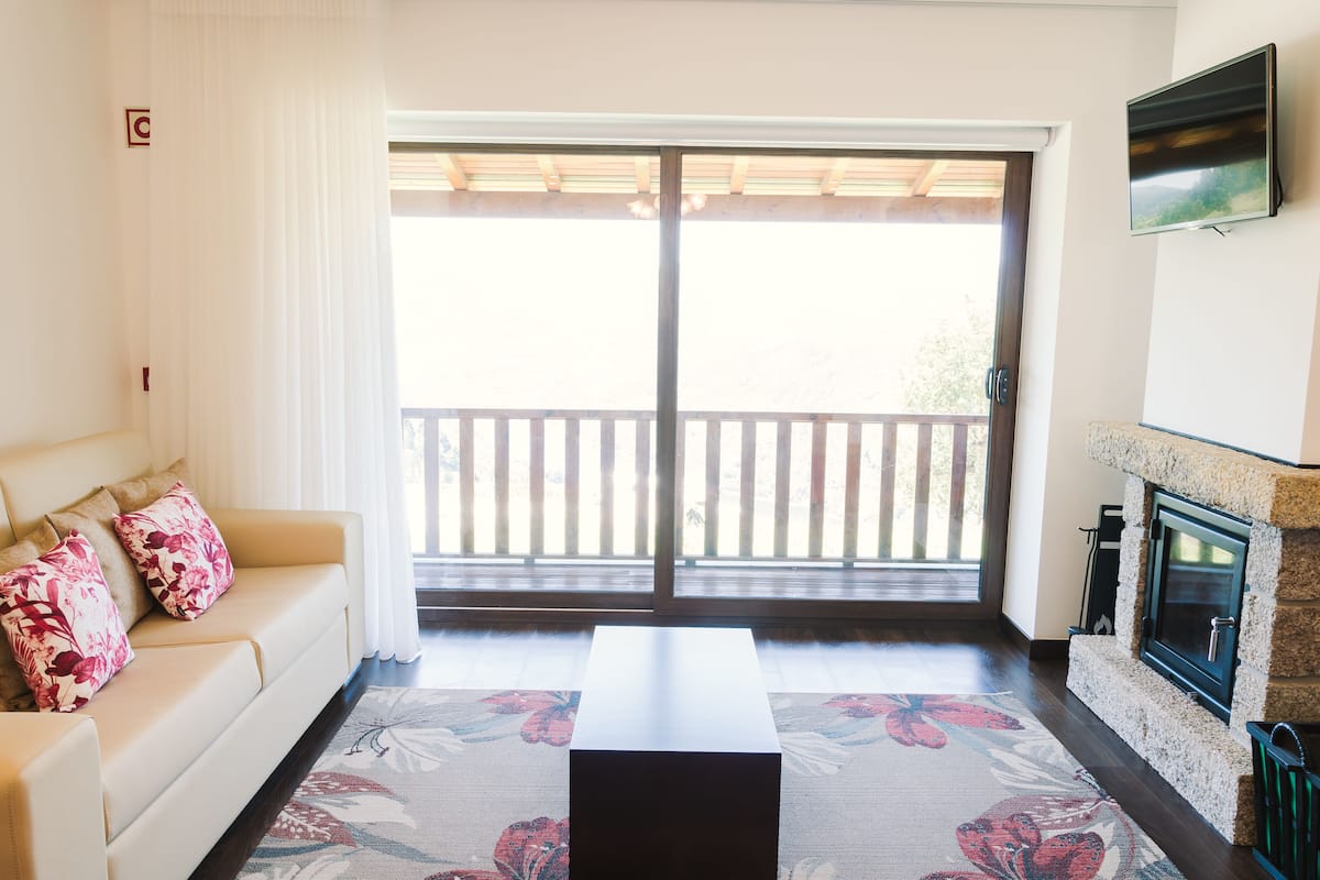 A living room with a sofa, a coffee table, a fireplace, and a sliding glass door leading to a balcony.