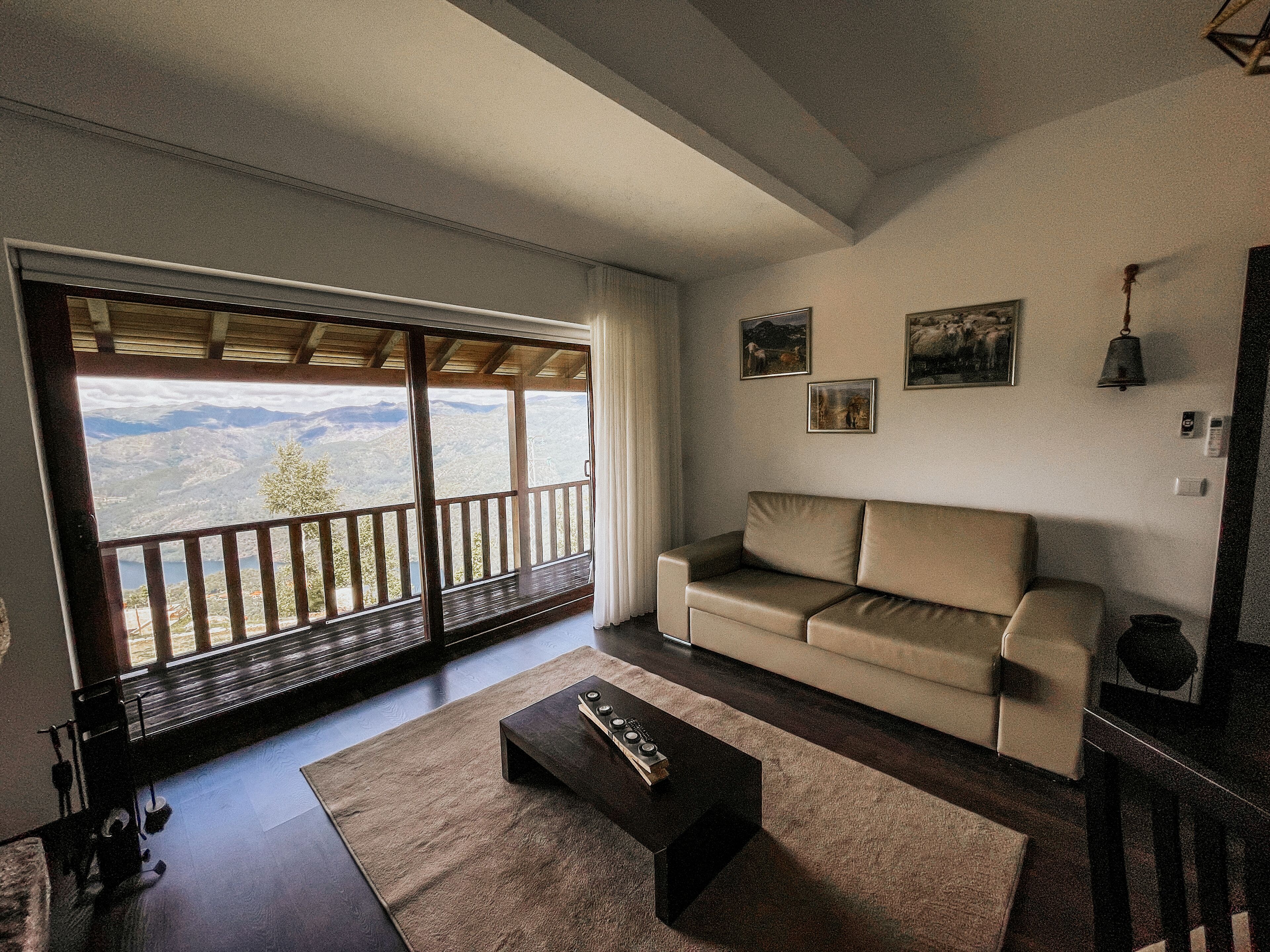 A living room with a large sliding glass door leading to a balcony with a mountain view.