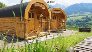 Two wooden cabins with "Gasthof Peschicht" signs, set against a mountainous backdrop. - Gasthof Pesbichl (Goldegg)