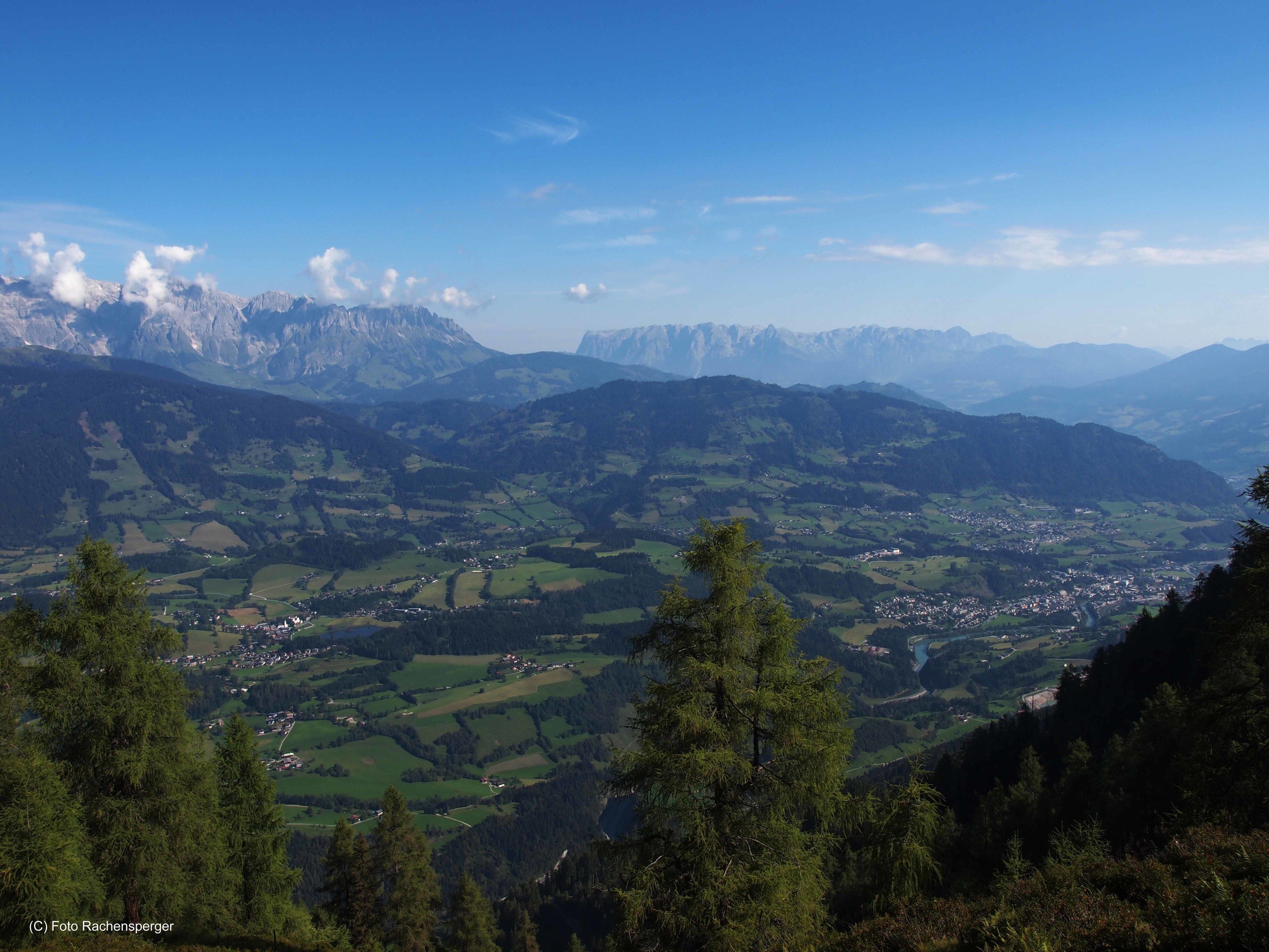 A panoramic view of a mountainous landscape with a valley below, featuring a small town and scattered buildings.