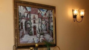 Een lijstwerk schilderij van een straatbeeld boven een houten console tafel met decoratieve objecten.