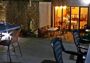 Un espacio para comer al aire libre con paredes de piedra, sillas de mimbre y mesas.
