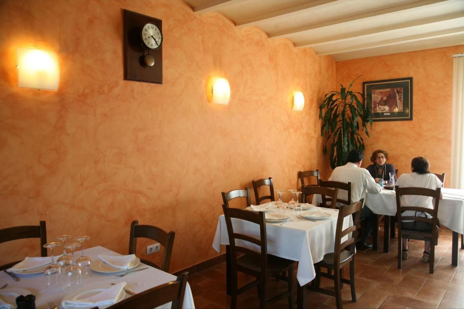 A restaurant with a rustic interior, featuring wooden tables and chairs, a clock on the wall, and warm lighting.