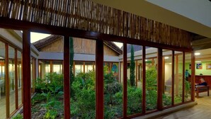 A spacious indoor area with a glass partition, wooden flooring, and a bamboo ceiling. - Mezena Resort and Spa (Lalibela)