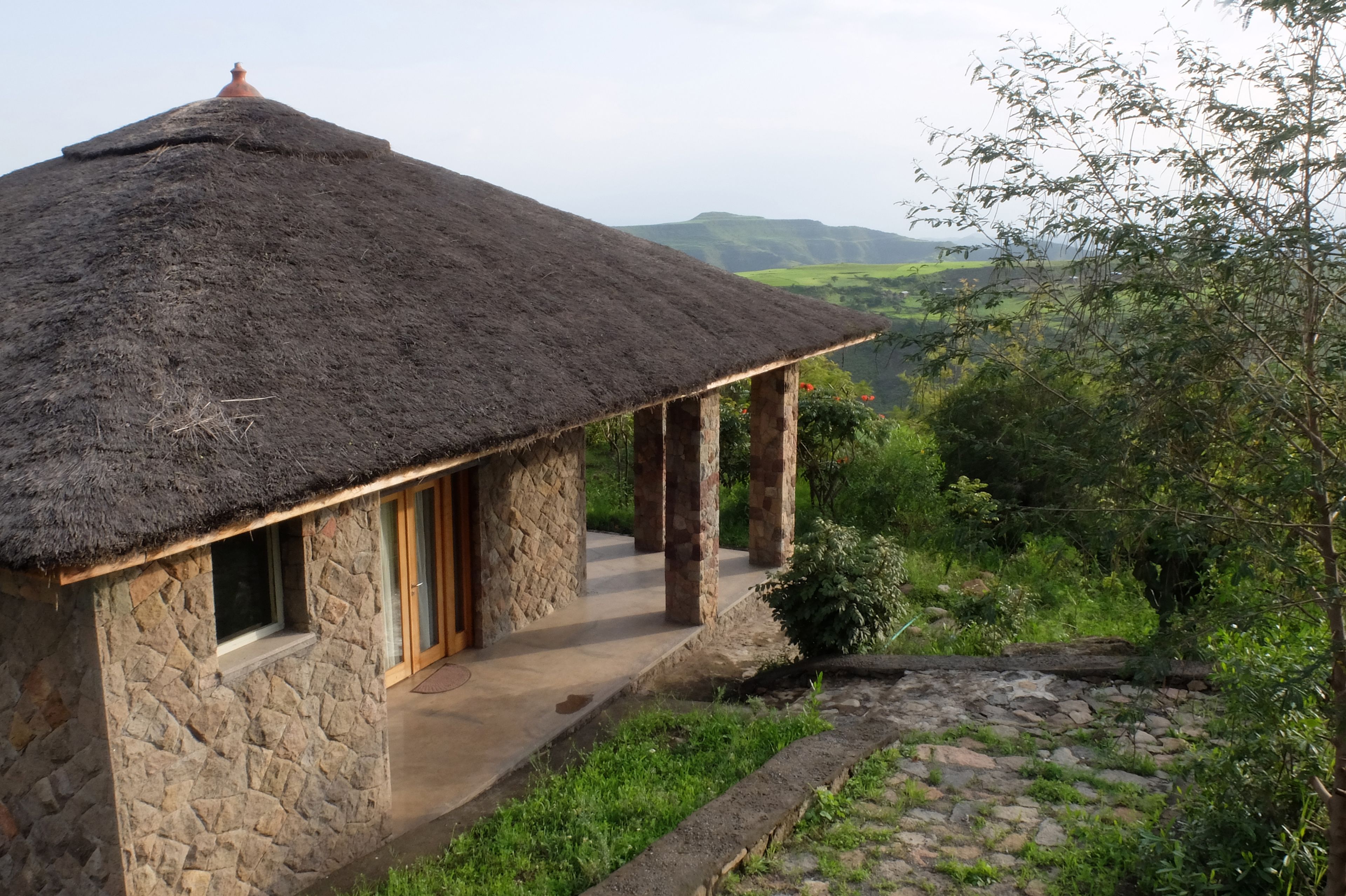 A stone house with a thatched roof, a wooden door, and a window.