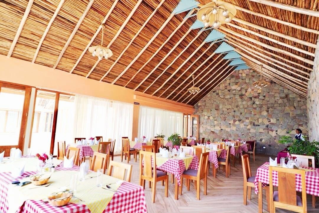 Een restaurant met houten tafels en stoelen, geruit tafelkleed en een stenen muur.