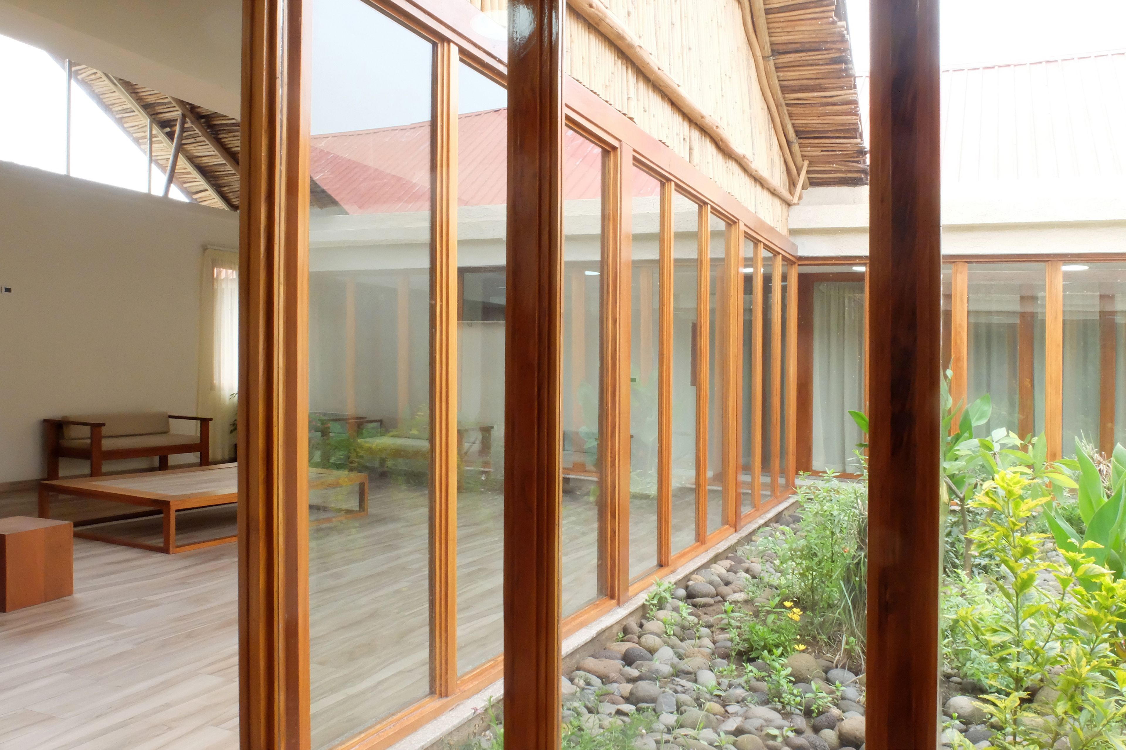 A modern interior with large glass windows, wooden flooring, and a seating area with benches.