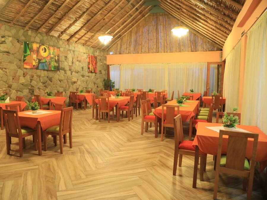 A restaurant with multiple tables and chairs, stone walls, and wooden flooring.