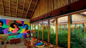 A room with a bamboo ceiling, large windows, and colorful abstract art on the wall. - Mezena Resort and Spa (Lalibela)