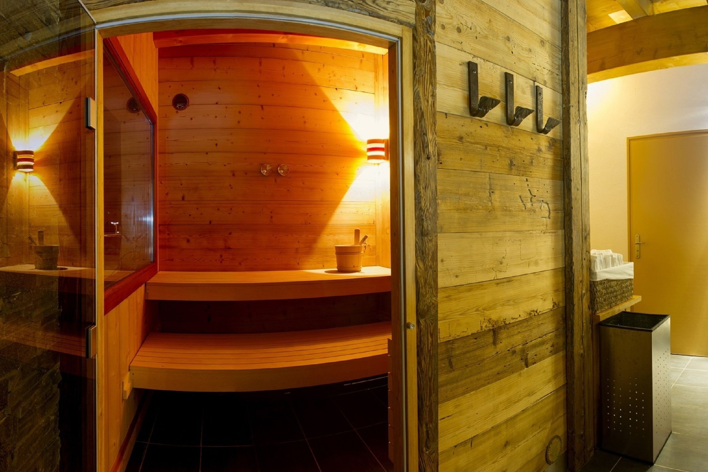 Eine Sauna mit Holzwänden und -bänken, einer Glastür und einem Handtuchhalter.