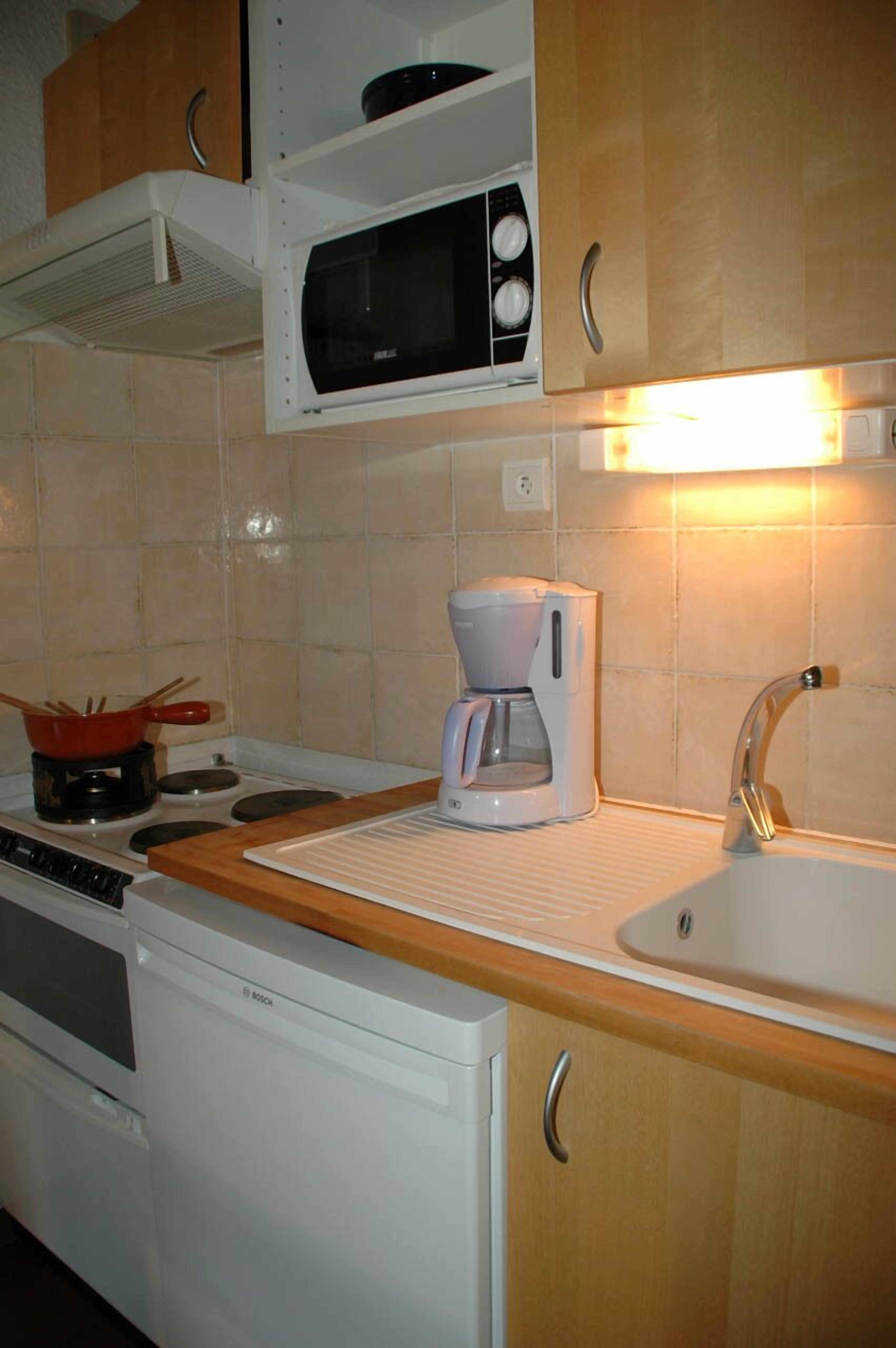 A kitchen with a microwave, coffee maker, and a sink.