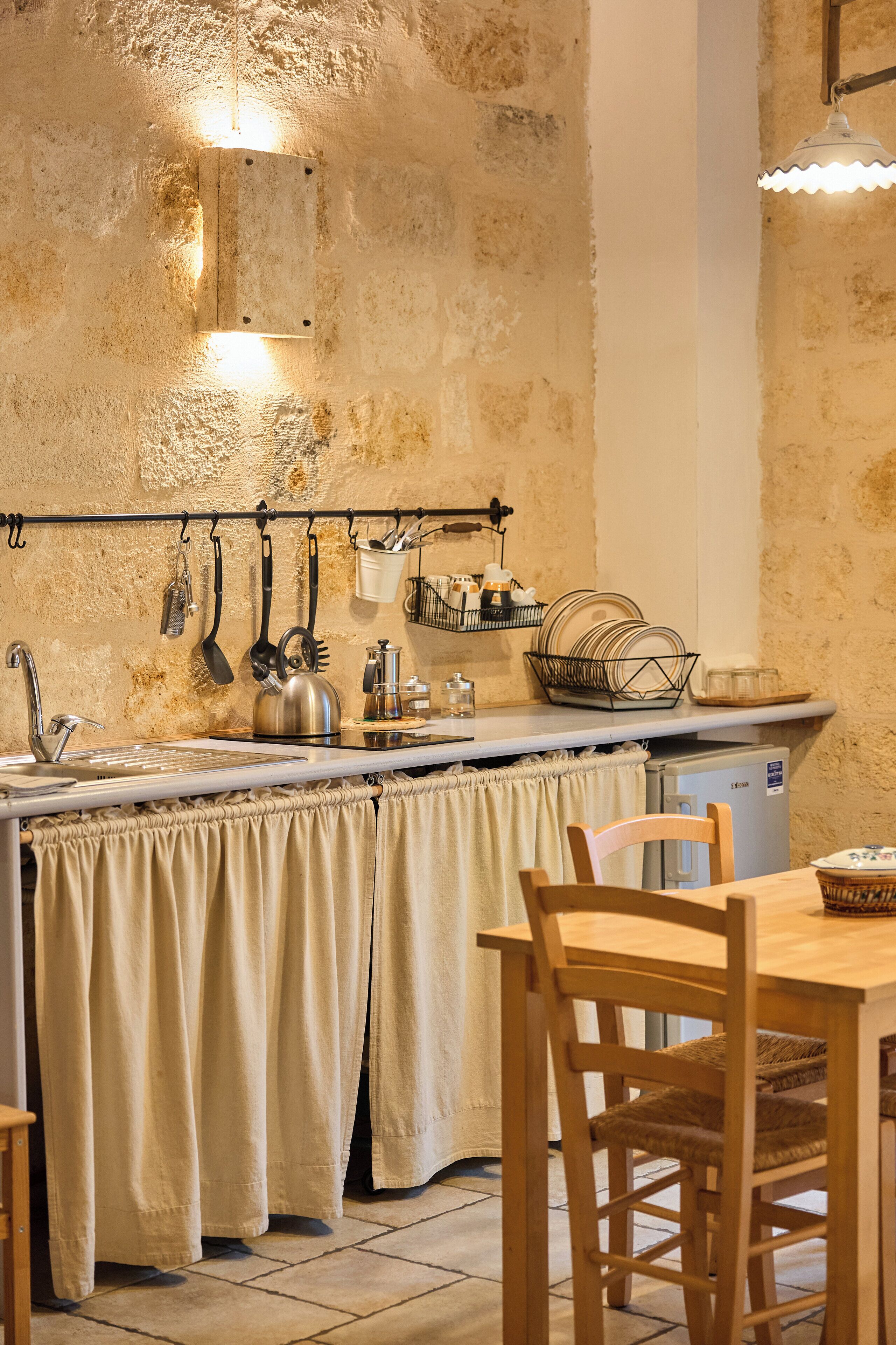 A kitchen with a rustic stone wall, a wooden table, and a chair.